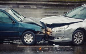 Two cars colliding head-on on a wet road